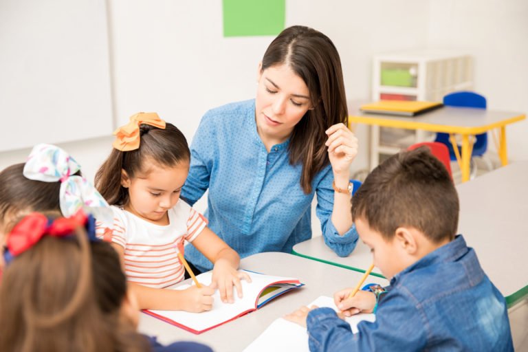 Teacher helping young children with schoolwork