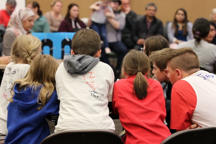 Group of kids huddled around a table participating in Battle of the Books