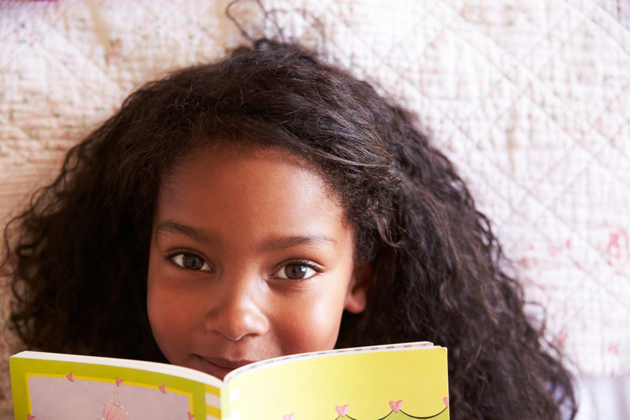 Young girl smiling, holding a book