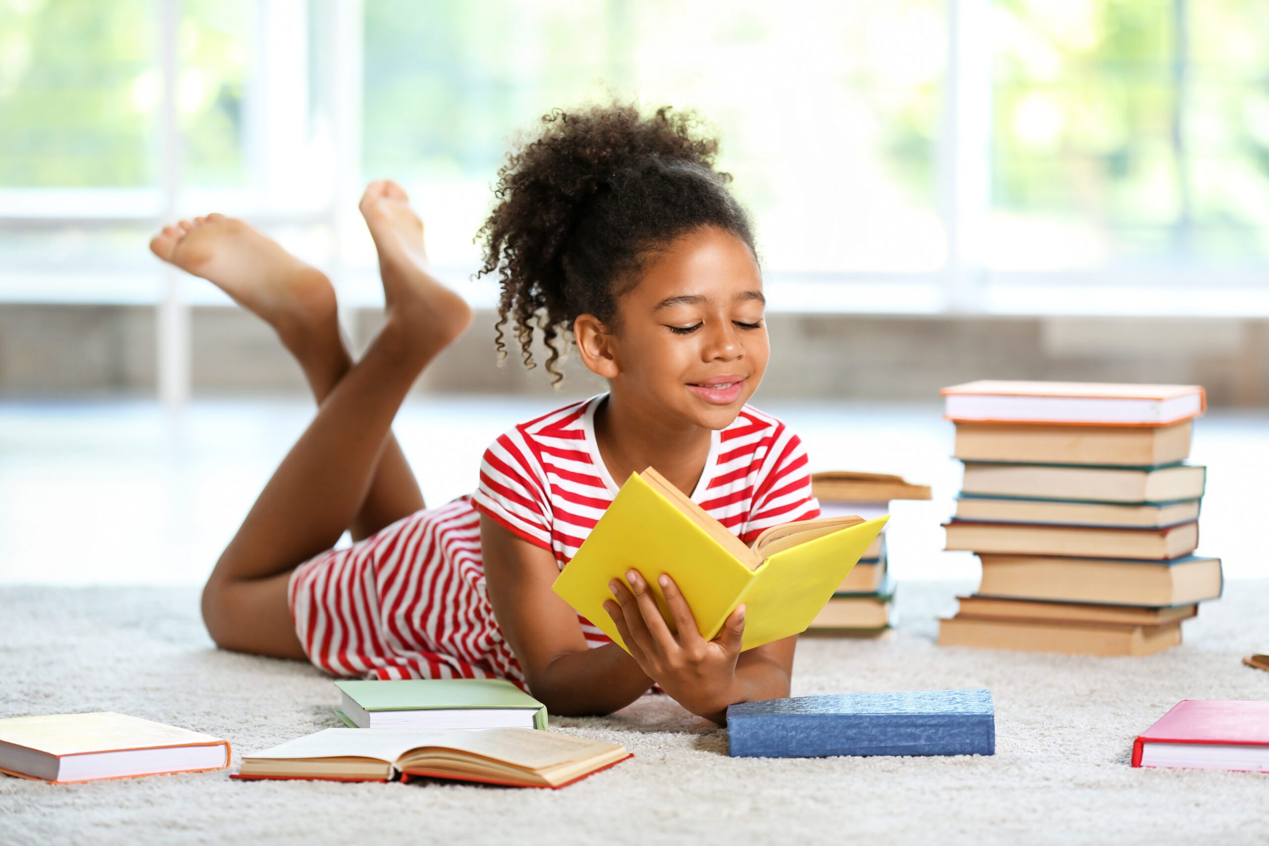 Young girl comfortably reading a book and smiling
