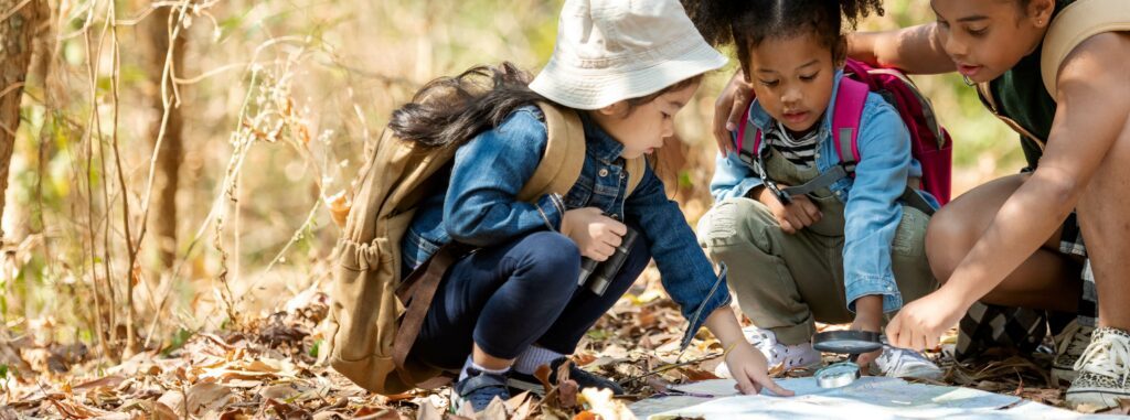 Group of children looking at map and exploring outdoors