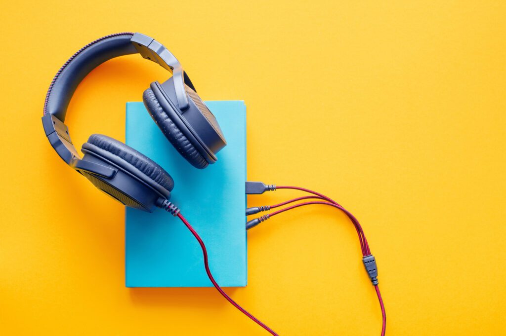 Headphones are connected to a book to portray Audiobook Appreciation Month