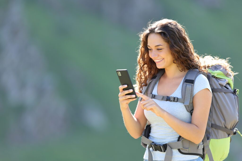 Happy hiker consulting smartphone while trekking