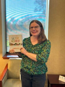 Library staff member holding up the cookbook "Salt, Fat, Acid, Heat" by Samin Nosrat