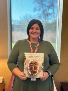 Library staff member holding up the cookbook "Half Baked Harvest Super Simple" by Tieghan Gerard