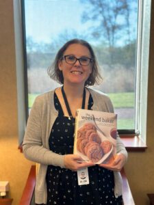 Library staff member holding up the cookbook "The Weekend Baker" by Abigail Johnson Dodge