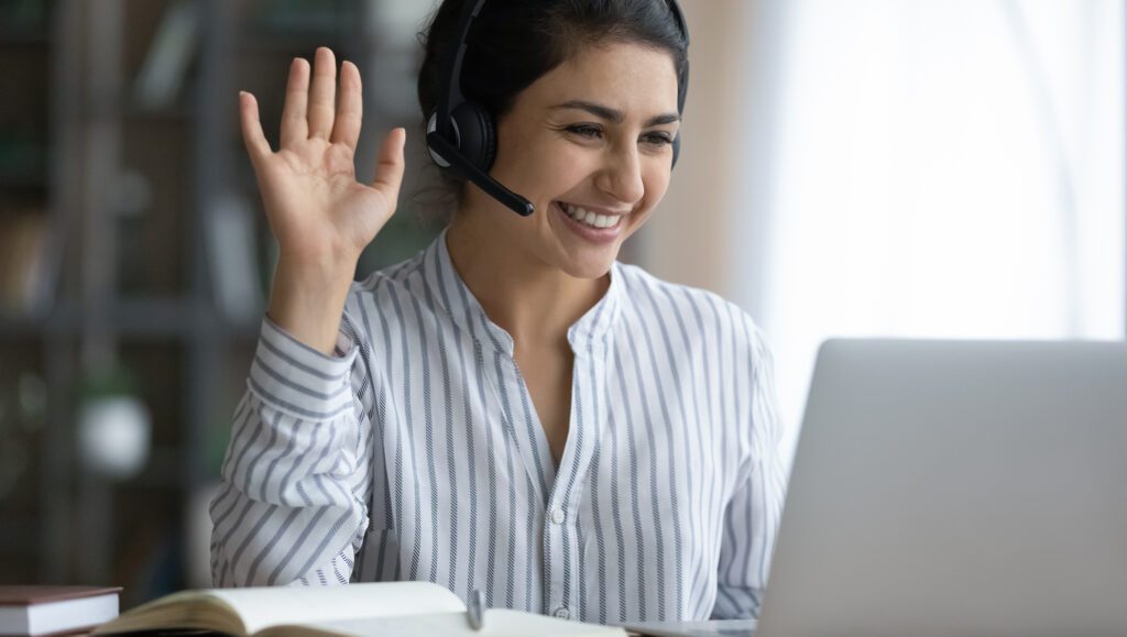 Person smiling and waving at laptop during virtual job interview