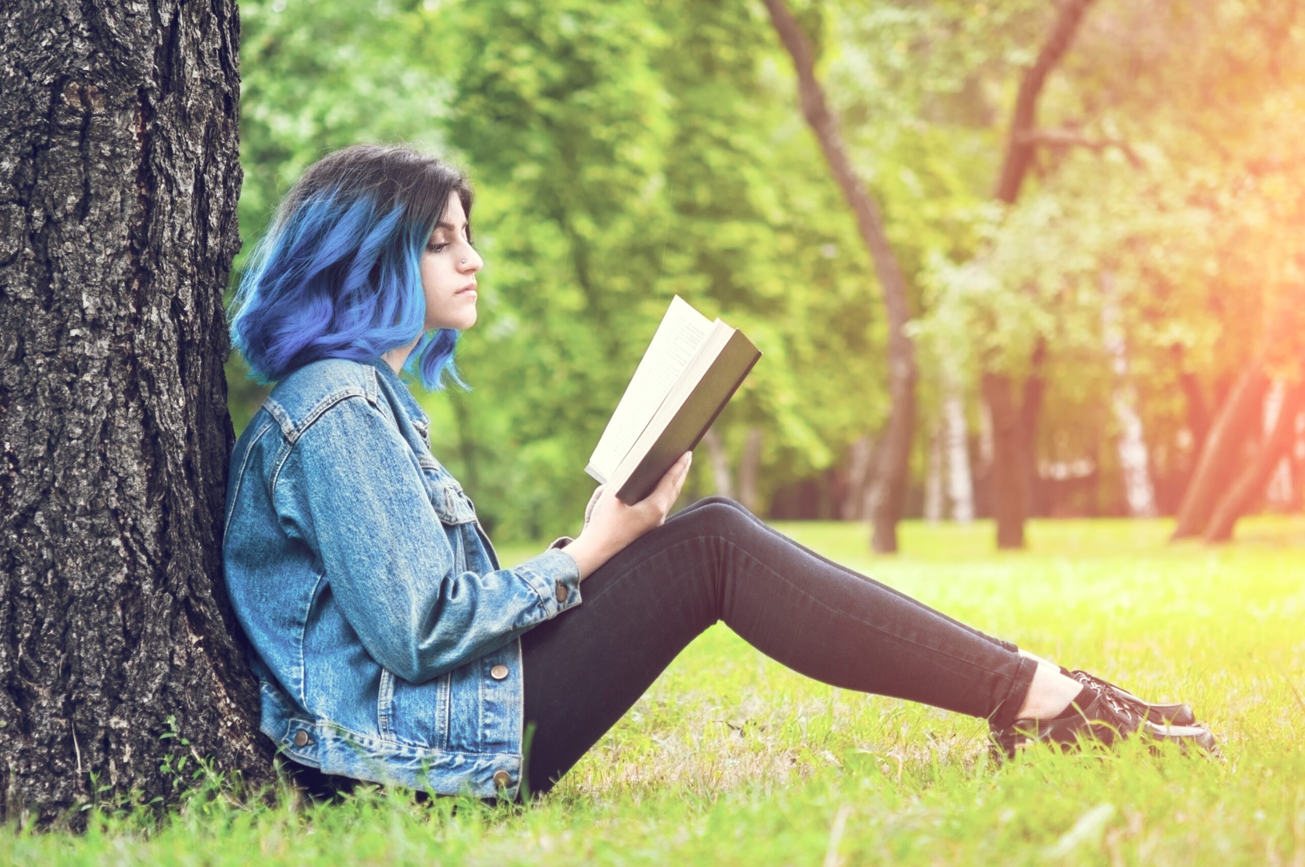 Teen girl reading a book outside.