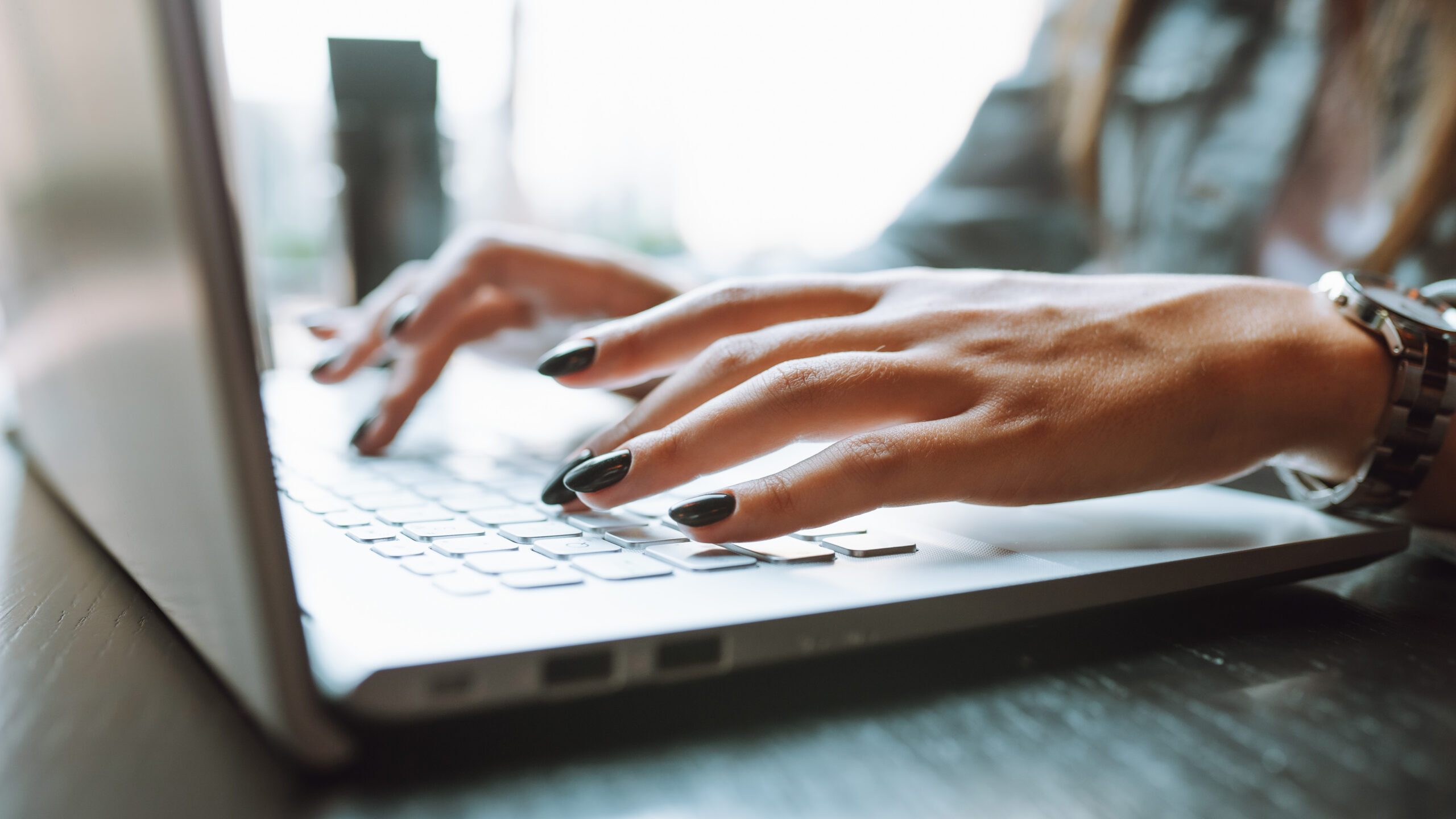 Closeup of person's hands typing on a laptop